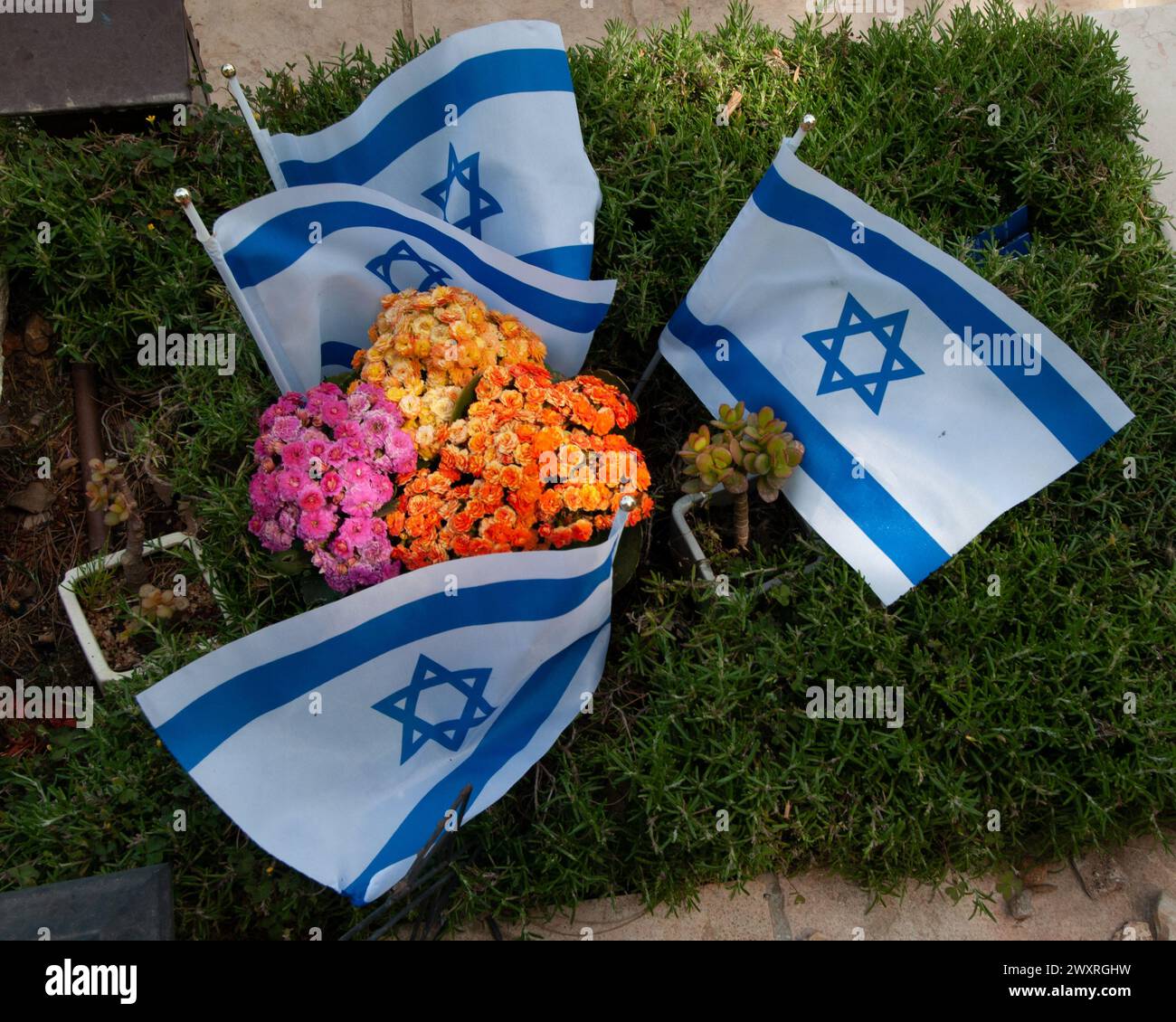 Piccole bandiere e fiori israeliani adornano la tomba di un soldato caduto delle forze di difesa israeliane nel Monte Cimitero militare di Herzl a Gerusalemme. Foto Stock