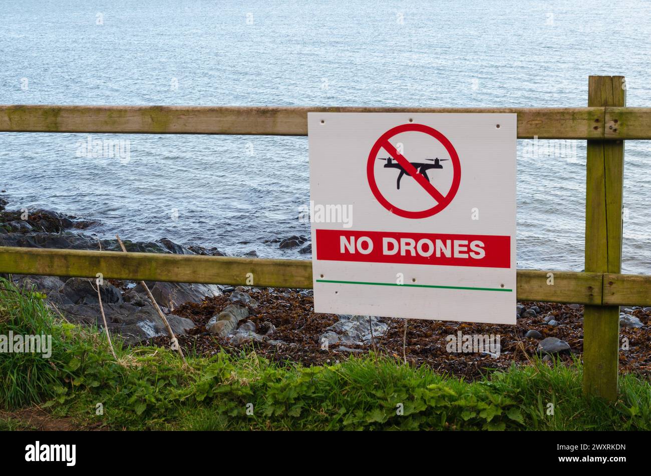 Cartello "no Drones" su una recinzione di legno vicino a un sentiero pubblico accanto a una spiaggia Foto Stock