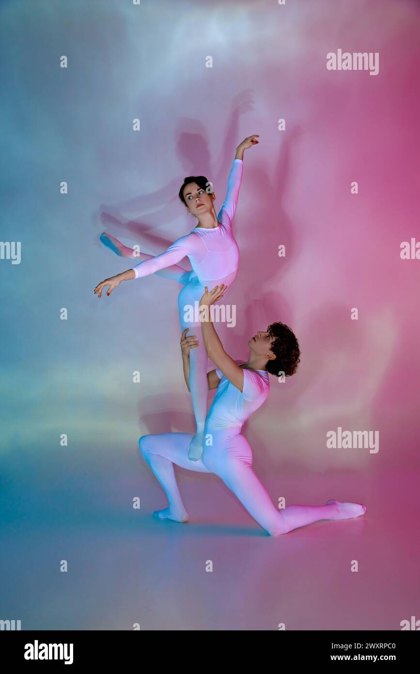 Ballerini di balletto maschili e femminili in cornicioni pastello che eseguono sollevamenti su sfondo gradiente. Foto Stock