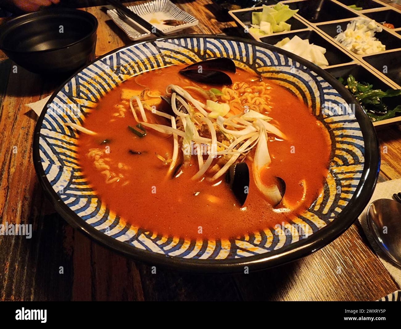 Ramen speziato coreano con cozze, germogli di soia, cipolle e altri ingredienti Foto Stock