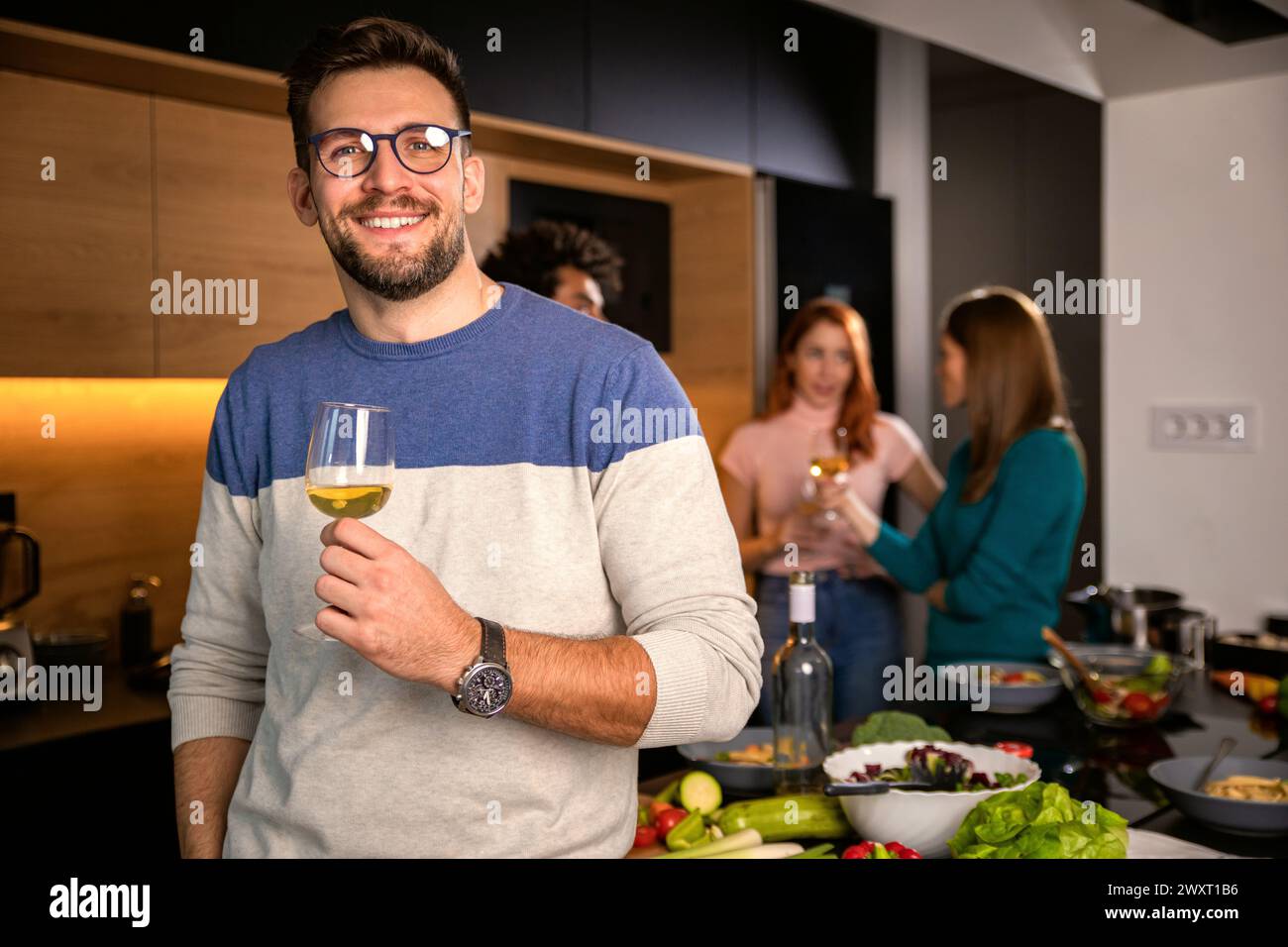 Ritratto di un uomo con un bicchiere di vino a cena con gli amici a casa. Foto Stock