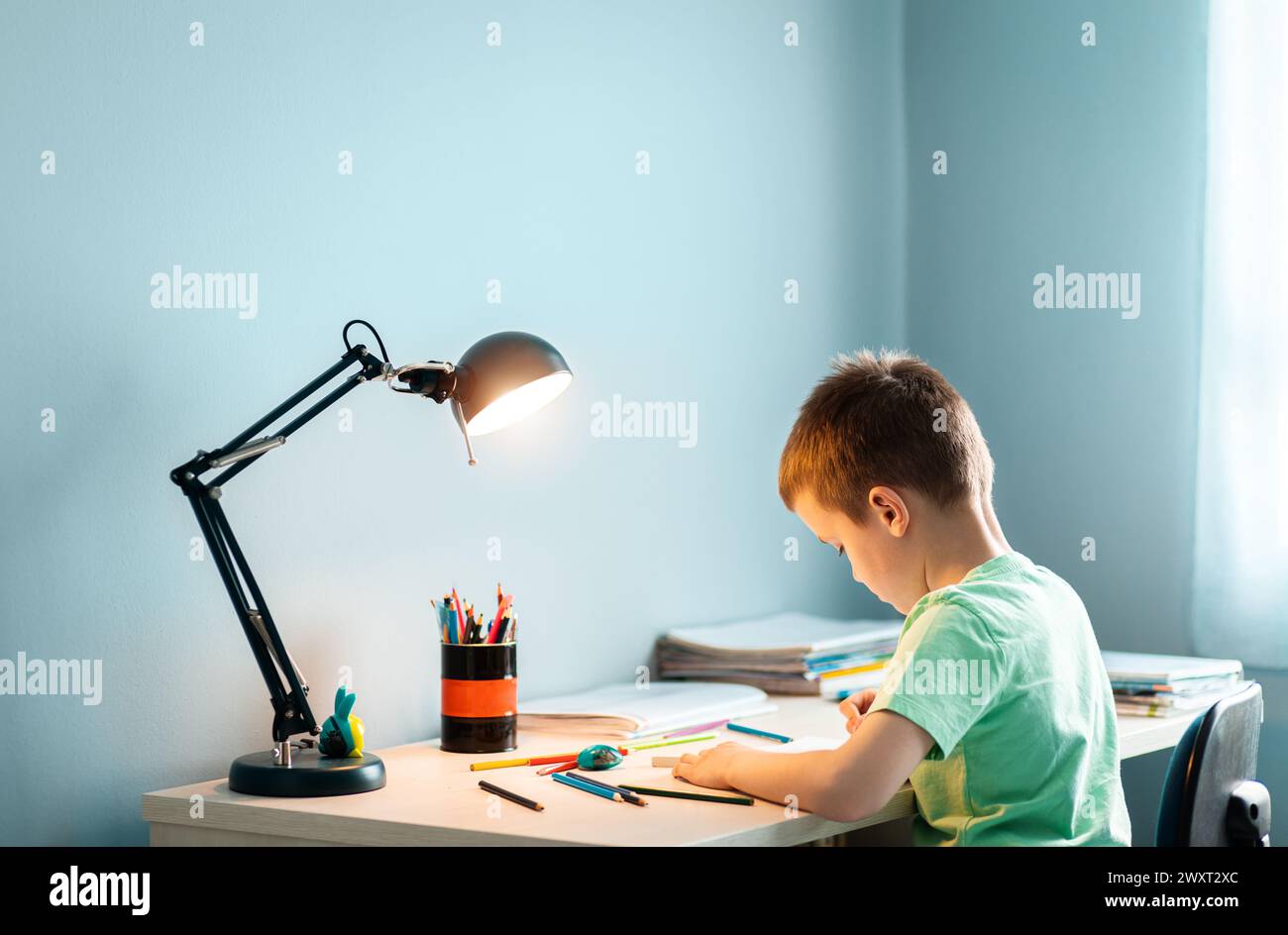 Ragazzo seduto alla scrivania a fare i compiti a casa. Foto Stock
