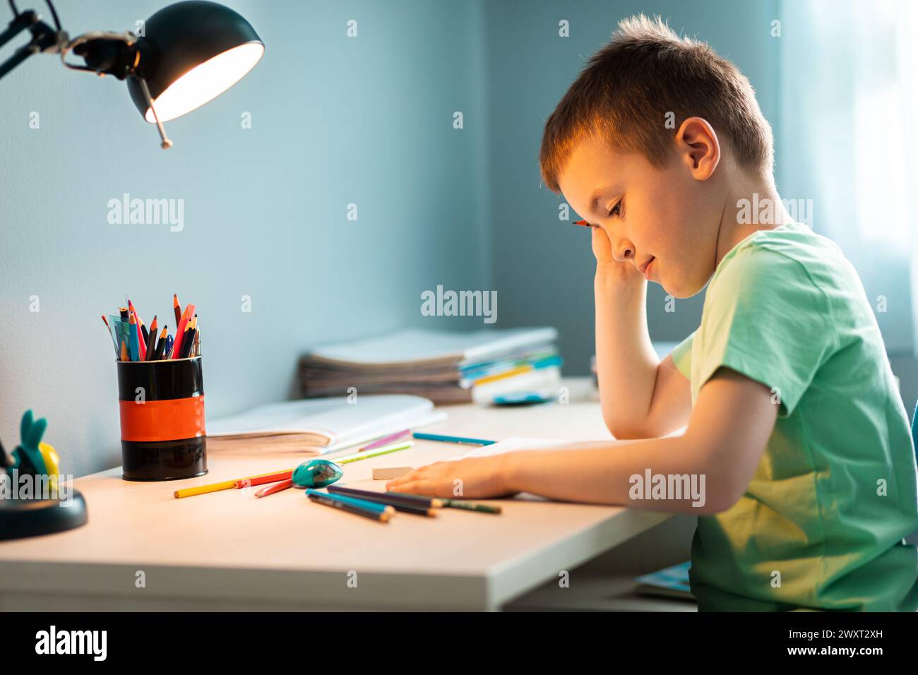 Ragazzo seduto alla scrivania a fare i compiti a casa. Foto Stock