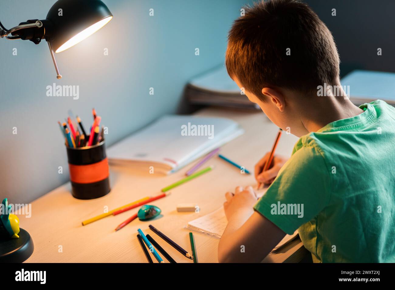 Ragazzo seduto alla scrivania a fare i compiti a casa. Foto Stock