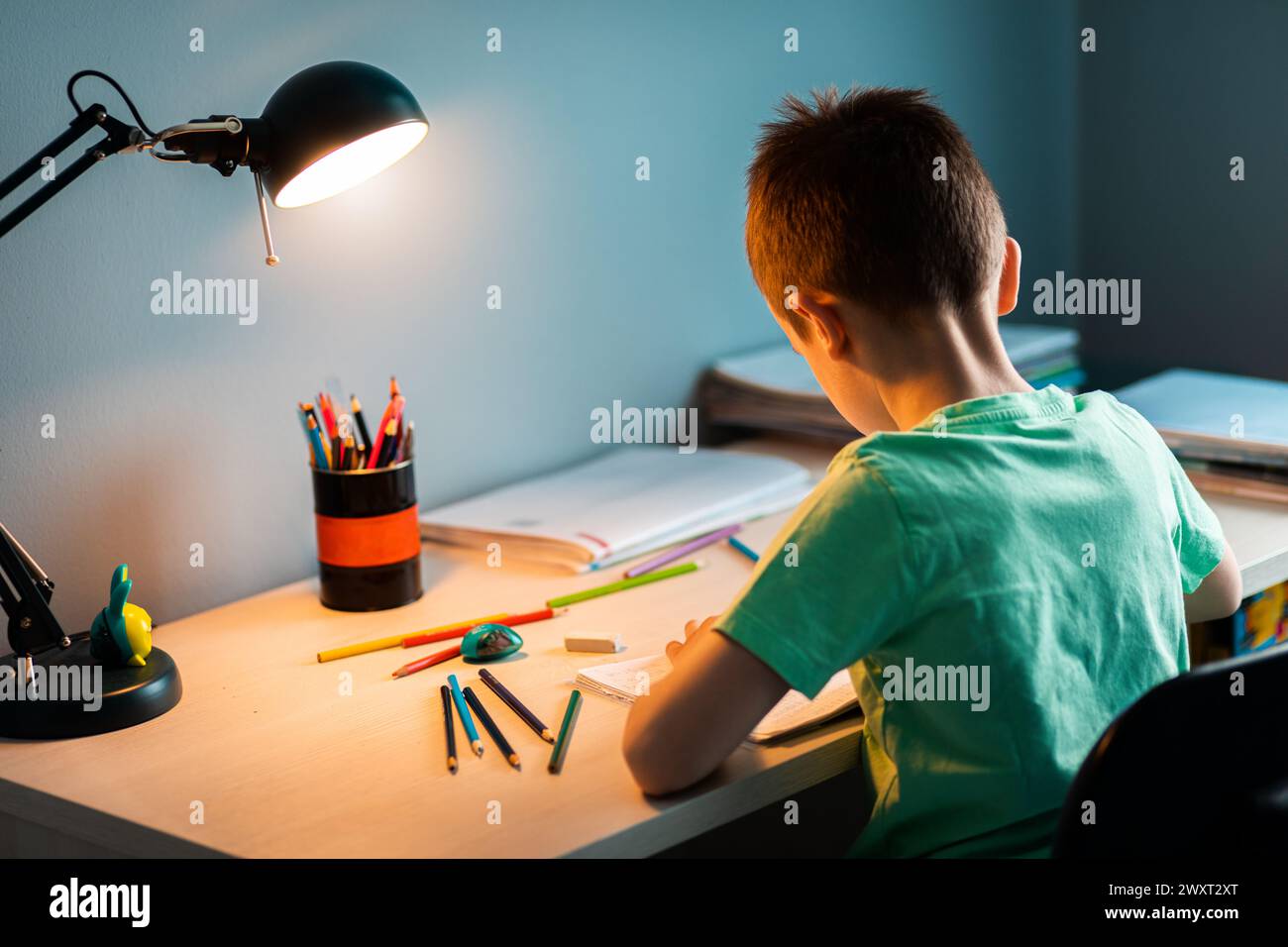 Ragazzo seduto alla scrivania a fare i compiti a casa. Foto Stock