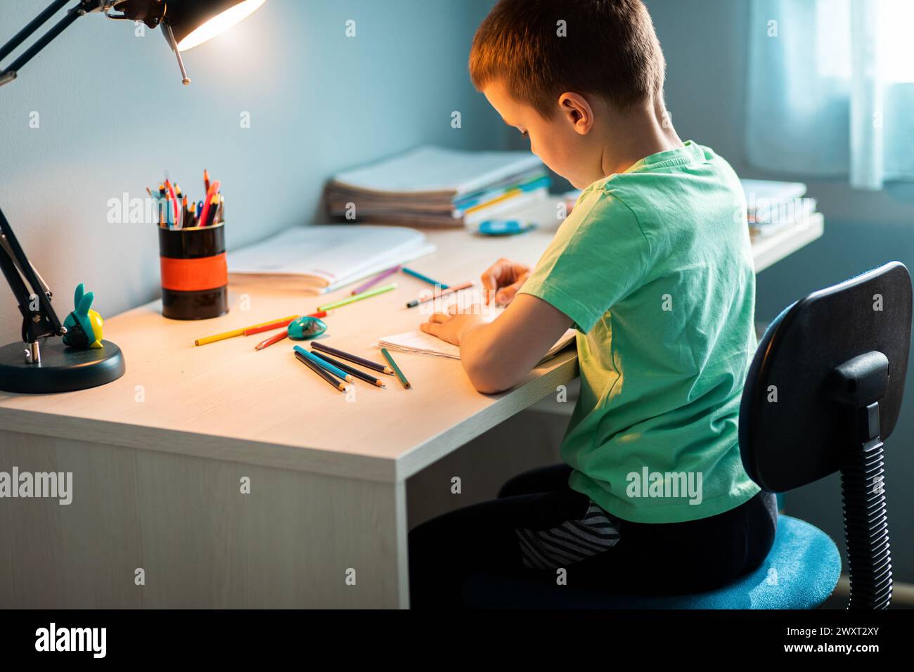 Ragazzo seduto alla scrivania a fare i compiti a casa. Foto Stock