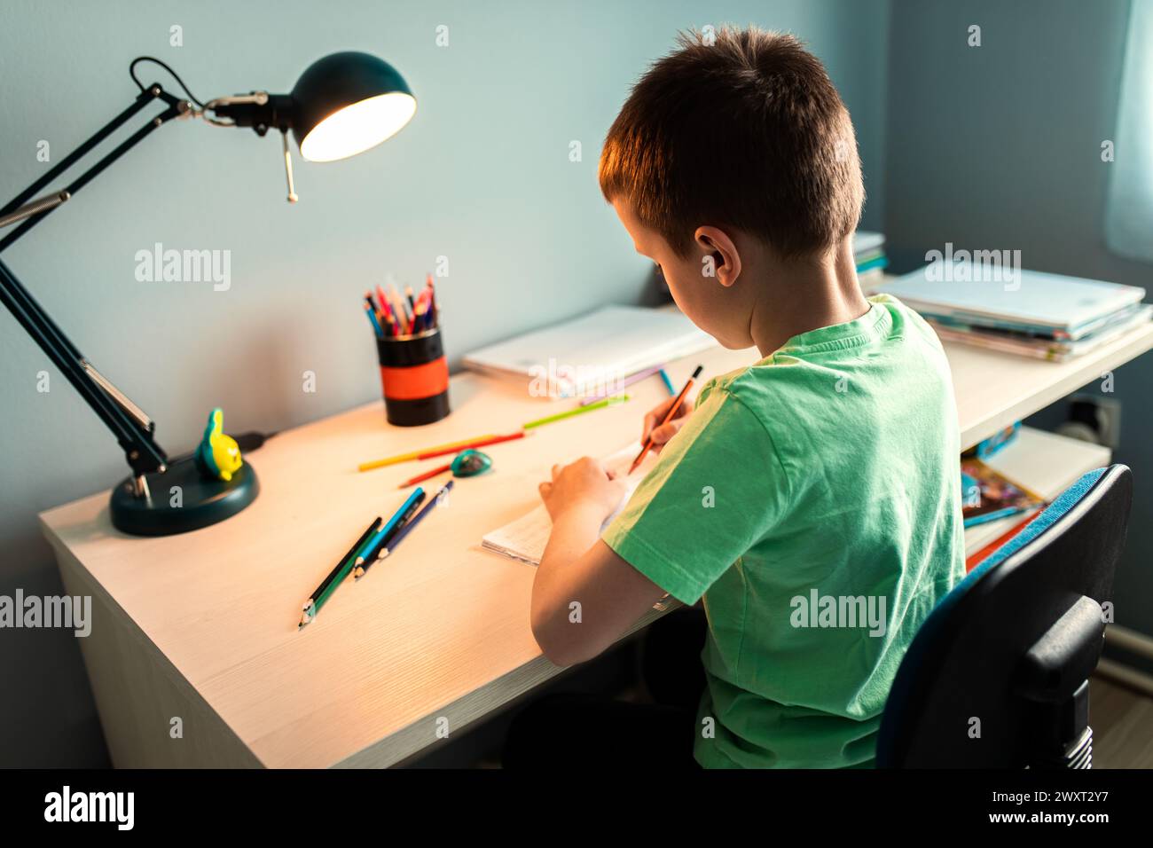 Ragazzo seduto alla scrivania a fare i compiti a casa. Foto Stock