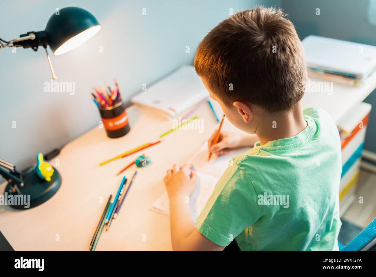 Ragazzo seduto alla scrivania a fare i compiti a casa. Foto Stock