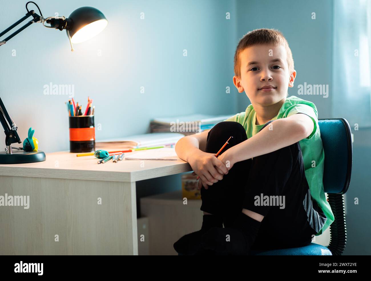 Ragazzo seduto alla scrivania a fare i compiti a casa. Foto Stock