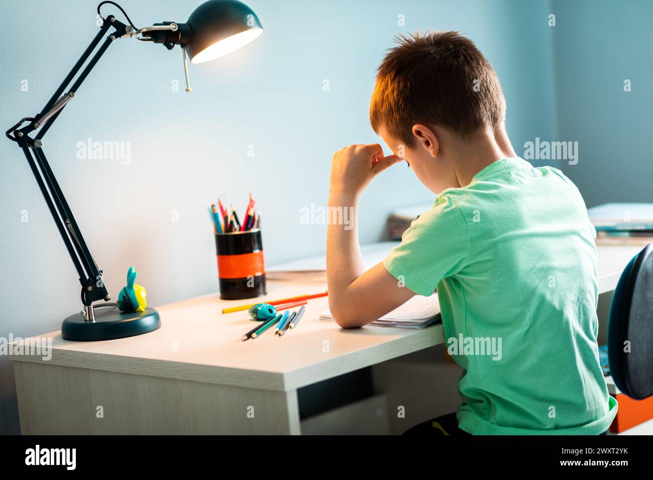 Ragazzo seduto alla scrivania a fare i compiti a casa. Foto Stock