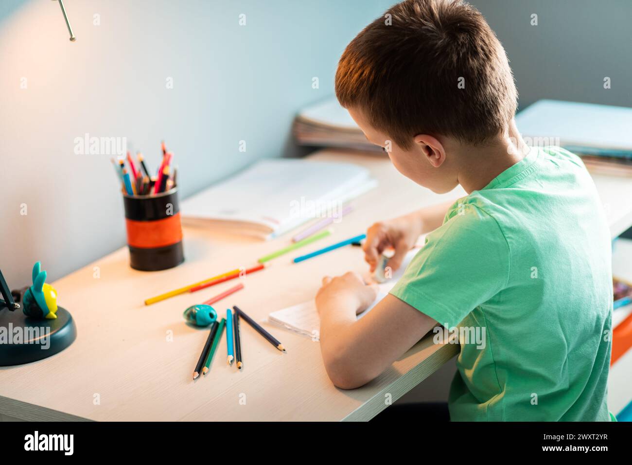 Ragazzo seduto alla scrivania a fare i compiti a casa. Foto Stock