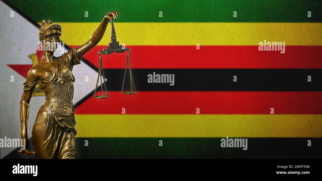 Primo piano di una piccola statuetta di bronzo di Lady Justice davanti a una bandiera dello Zimbabwe. Foto Stock