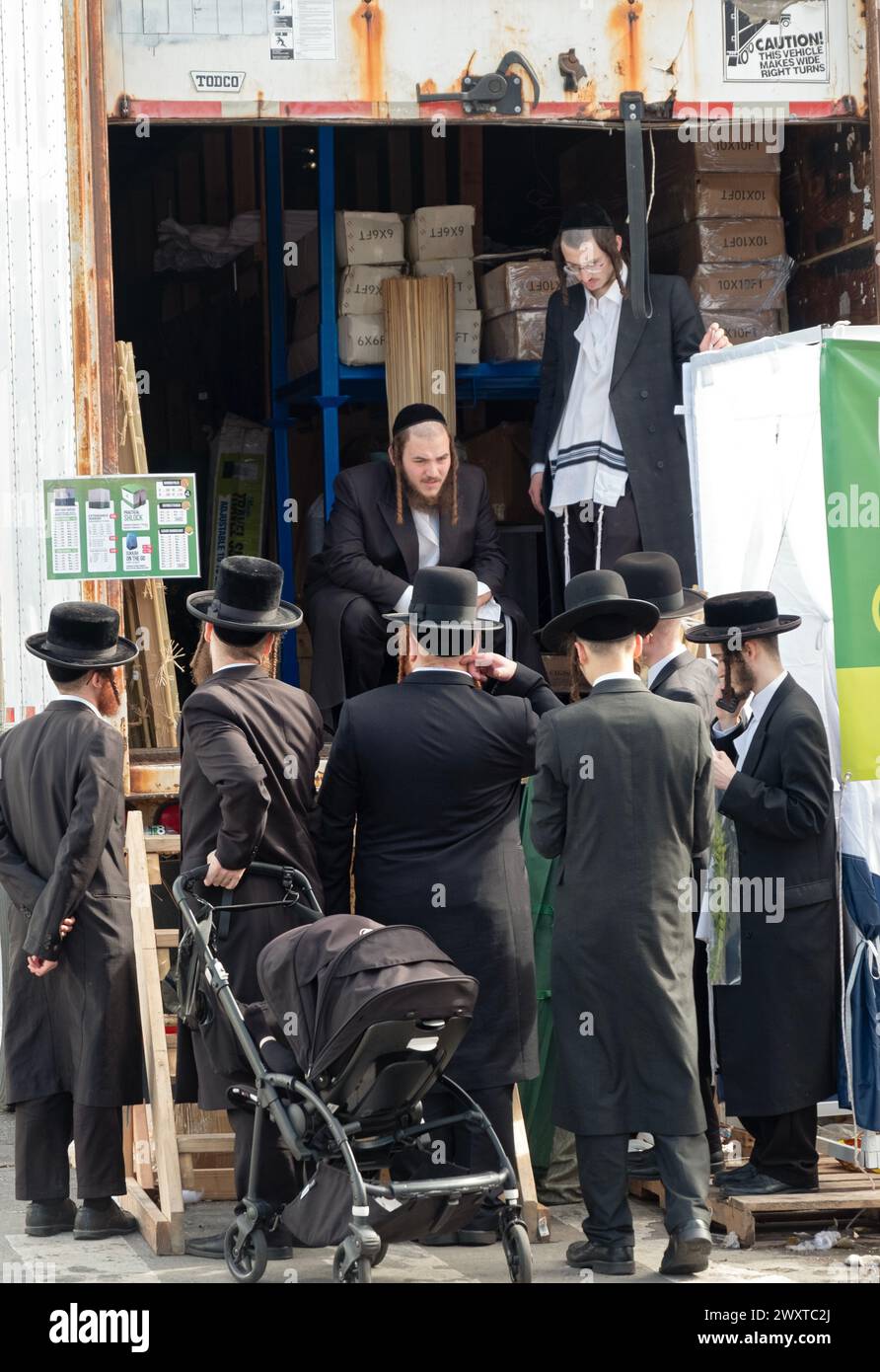 Un gruppo di ebrei ortodossi si trova accanto a un grande negozio di articoli prefabbricati e fai da te Sukkah. A Williamsburg, Brooklyn, New York. Foto Stock