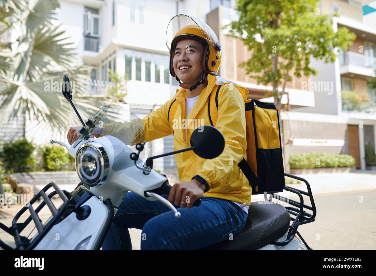 Corriere sorridente in moto con casco Foto Stock