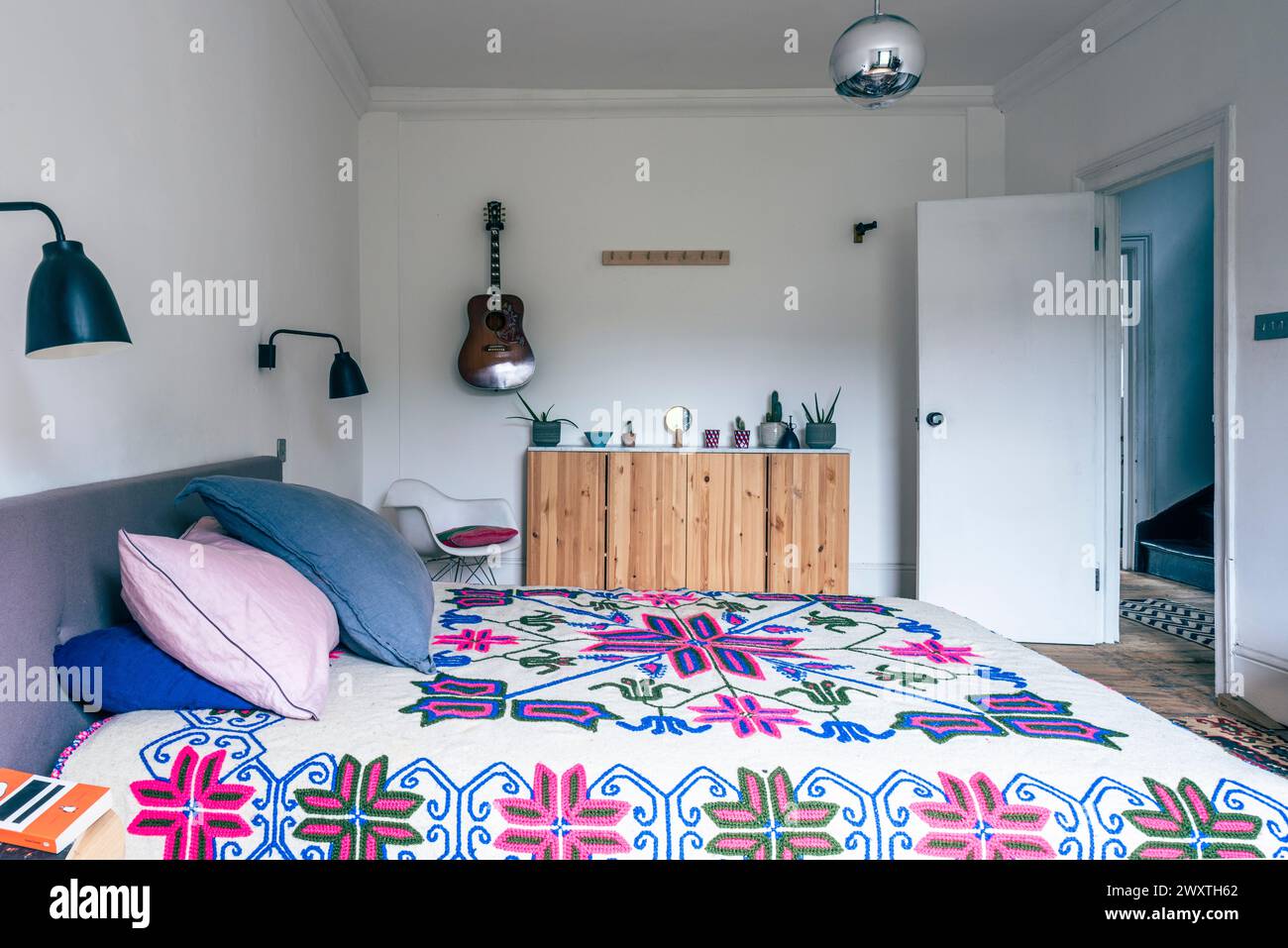 Copriletto retrò anni '70 con chitarra e porta aperta nella casa di East London, Regno Unito Foto Stock