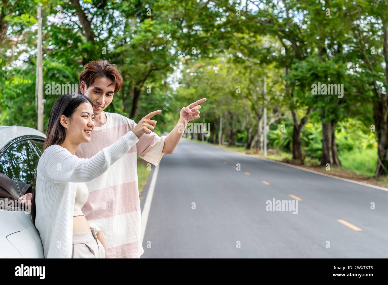 Coppia che punta vicino alla macchina con alberi sullo sfondo Foto Stock