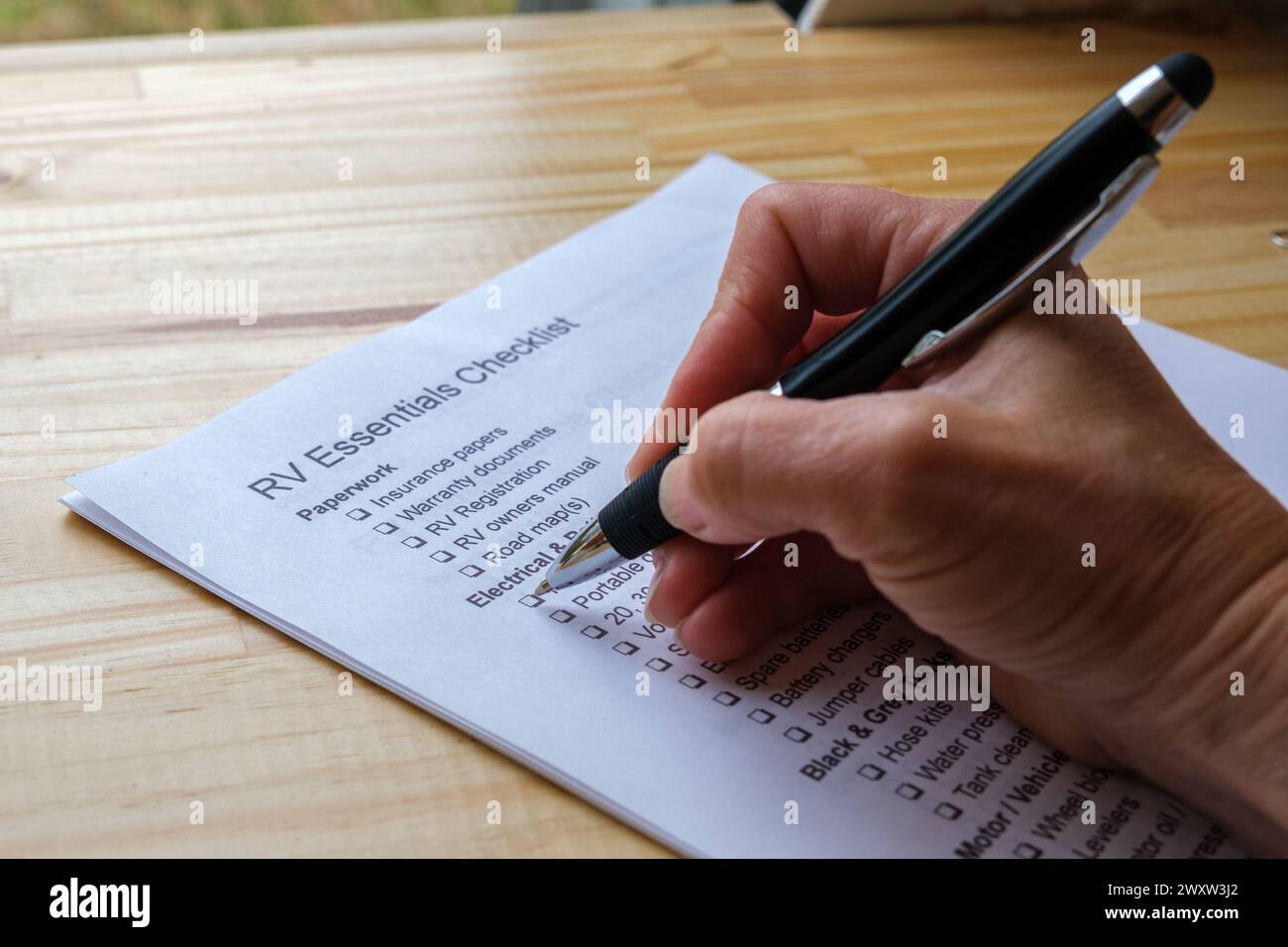 Mano con una penna che spunta le caselle nell'elenco di controllo RV Essentials Foto Stock
