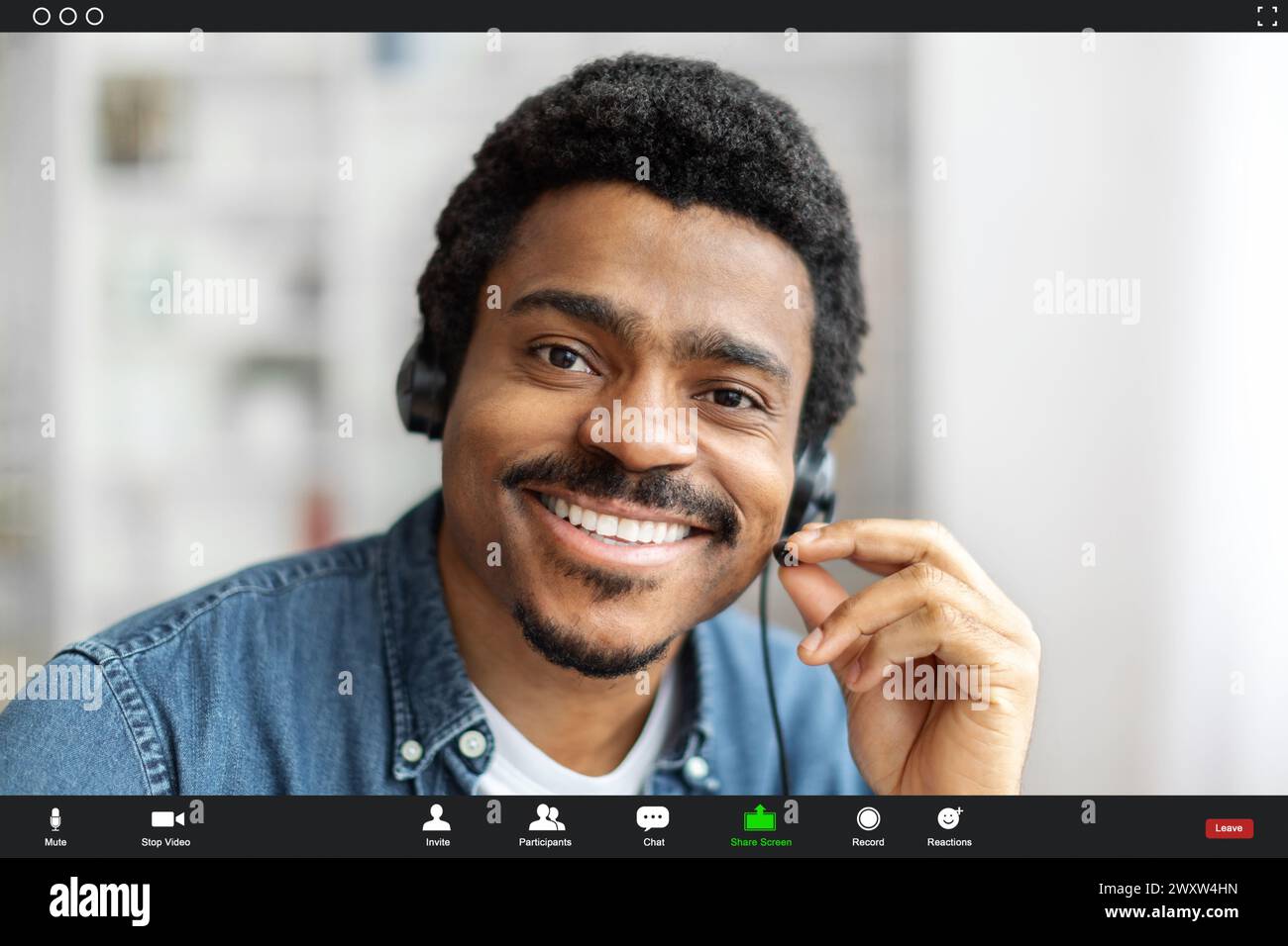 Uomo sorridente con cuffie in un ambiente interno luminoso, scatto interfaccia Foto Stock