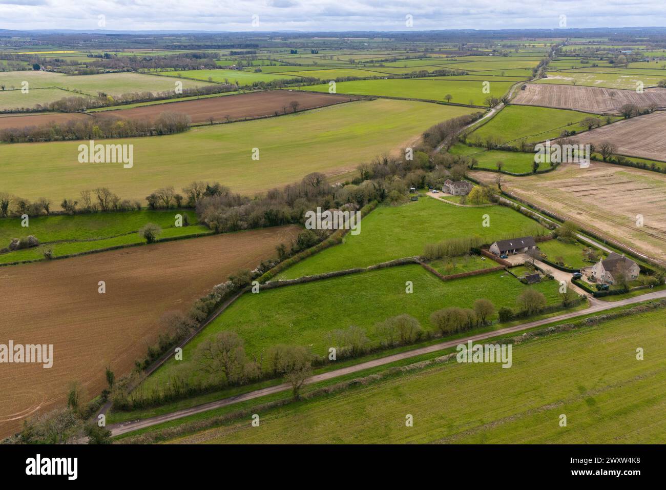 Una vista che guarda verso il sito proposto della fattoria solare Lime Down con la vecchia strada romana, andando diagonalmente attraverso il paesaggio in lontananza, nella campagna del Wiltshire vicino a Malmesbury e Sherston. Data foto: Martedì 2 aprile 2024. Foto Stock