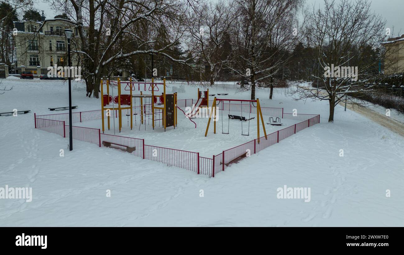 Fotografia con drone del parco giochi per bambini coperto dalla neve durante le nuvolose giornate invernali Foto Stock