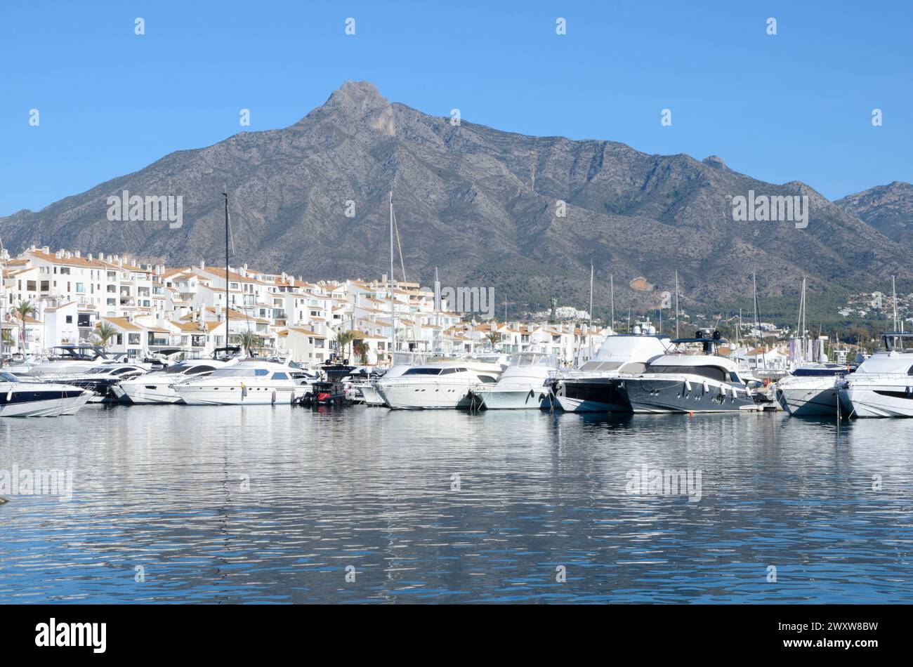Marbella, Spagna - 10 dicembre 2023: Barche bianche e case a Port Banus ai piedi della montagna a Marbella, Andalusia, Spagna. Foto Stock