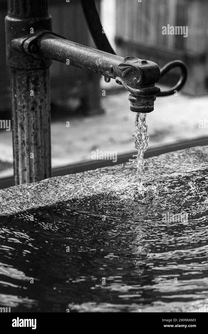 Un primo piano di acqua che scorre da un rubinetto da giardino d'epoca o da un rubinetto. Foto Stock