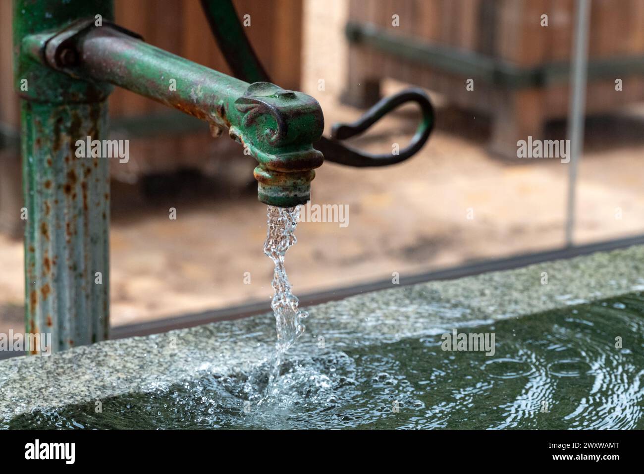 Un primo piano di acqua che scorre da un rubinetto da giardino d'epoca o da un rubinetto. Foto Stock