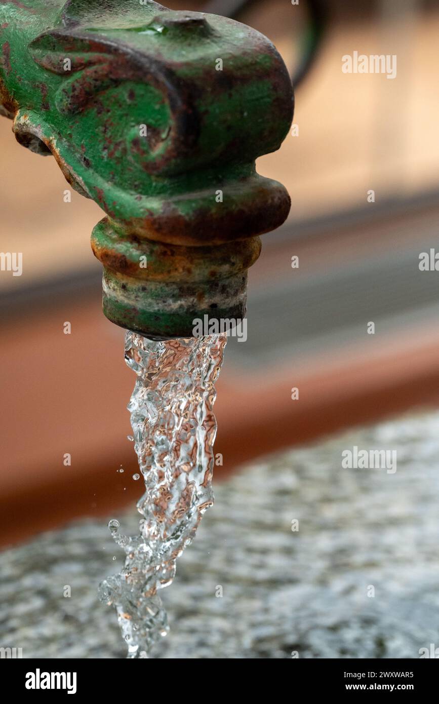 Un primo piano di acqua che scorre da un rubinetto da giardino d'epoca o da un rubinetto. Foto Stock