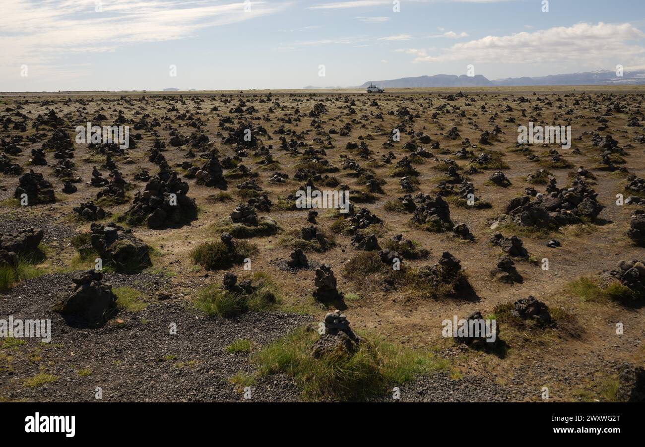 Numerosi cumuli di roccia (cairns) nella valle di Laufskalavarda, nel sud dell'Islanda, con un'auto bianca sullo sfondo Foto Stock