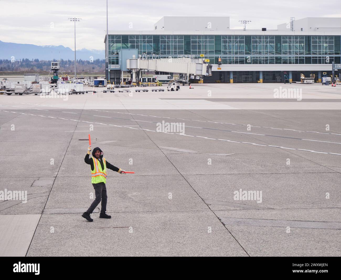 Aircraft marshall in giubbotto ad alta visibilità che dirige aeromobili su piazzale asfaltato in aeroporto, aereo o pilota POV. Foto Stock