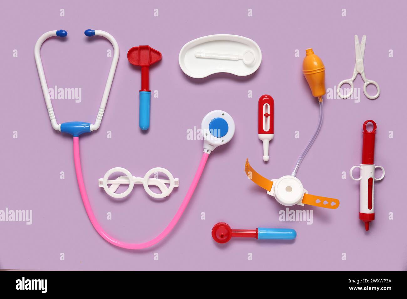 Stetoscopio giocattolo con termometro e martello riflettente su sfondo lilla. Vista dall'alto Foto Stock
