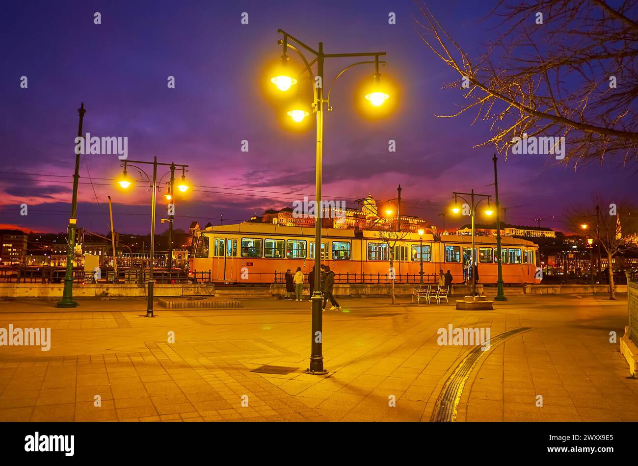 Illuminazione serale luminosa di Piazza Vigado con vista sul tram e sul Castello di Buda sullo sfondo, Budapest, Ungheria Foto Stock