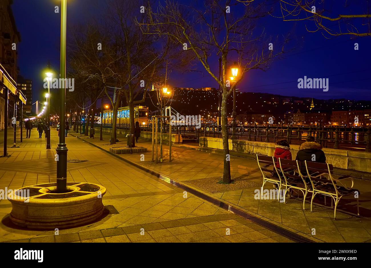 Goditi la passeggiata serale sul molo Jane Haining, osservando i tram, la collina Gellert, il ponte Elisabetta e il Danubio, Budapest, Ungheria Foto Stock