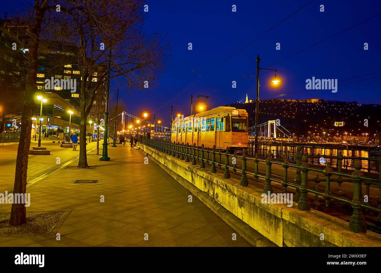 Il tram giallo retrò corre fino al Ponte Elisabetta nella città serale di Budapest, Ungheria Foto Stock