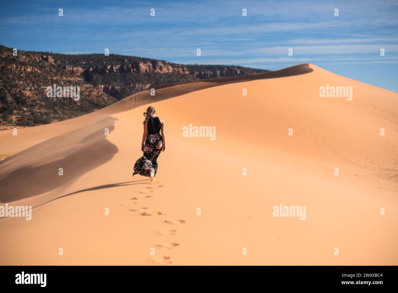 Donna che cammina su una duna di sabbia nel deserto nel Coral Pink Sand Dunes State Park, Utah Foto Stock