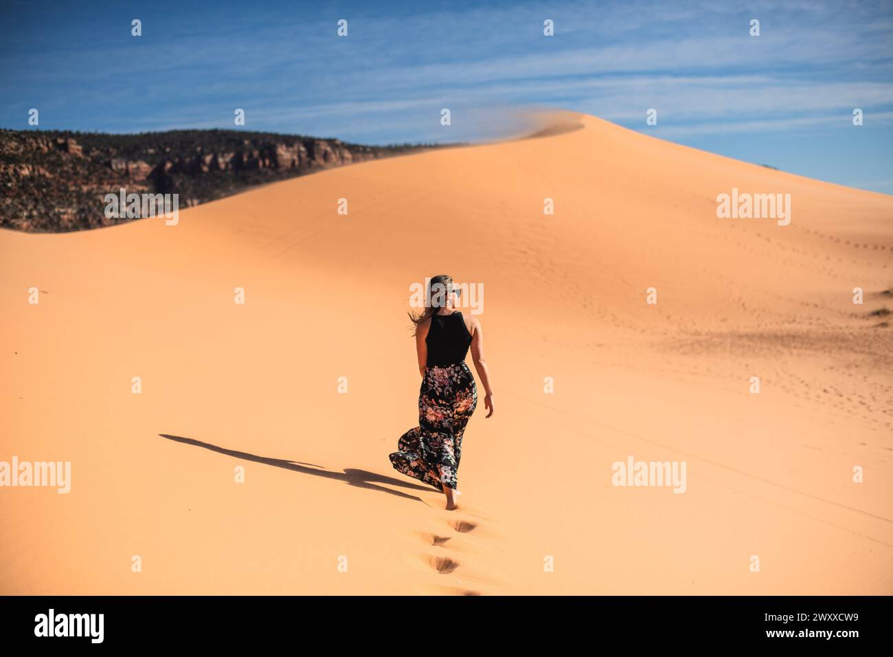 Donna che cammina su una duna di sabbia nel deserto nel Coral Pink Sand Dunes State Park, Utah Foto Stock