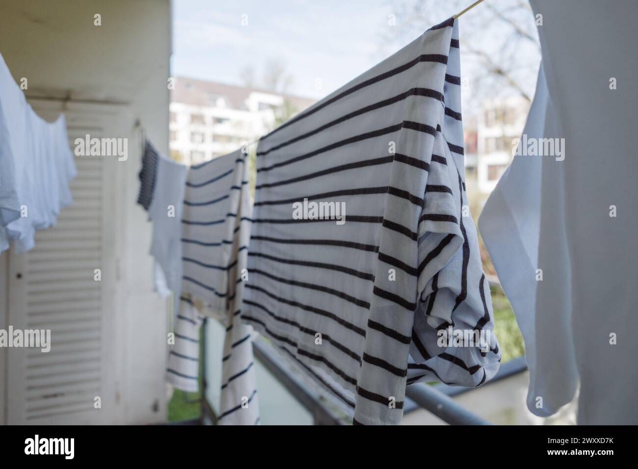 Un'immagine ravvicinata di vestiti appena lavati appesi ad asciugare su una ringhiera del balcone. Foto Stock