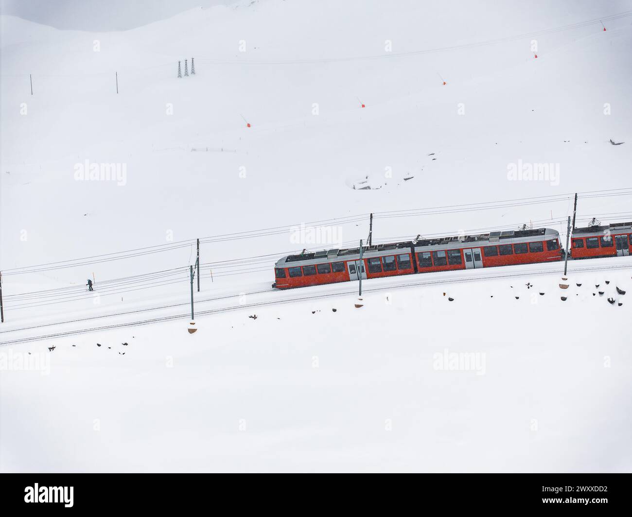 Treno rosso brillante nel paesaggio innevato con Walker, zona sciistica di Zermatt Foto Stock