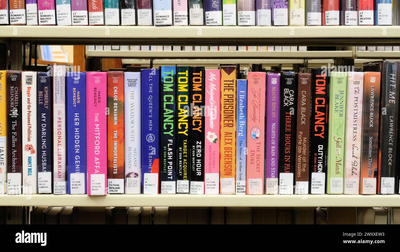 Scaffale della biblioteca con grandi edizioni cartacee di libri dell'autore americano Tom Clancy; romanzi e romanzi polizieschi, spie, storici e militari. Foto Stock