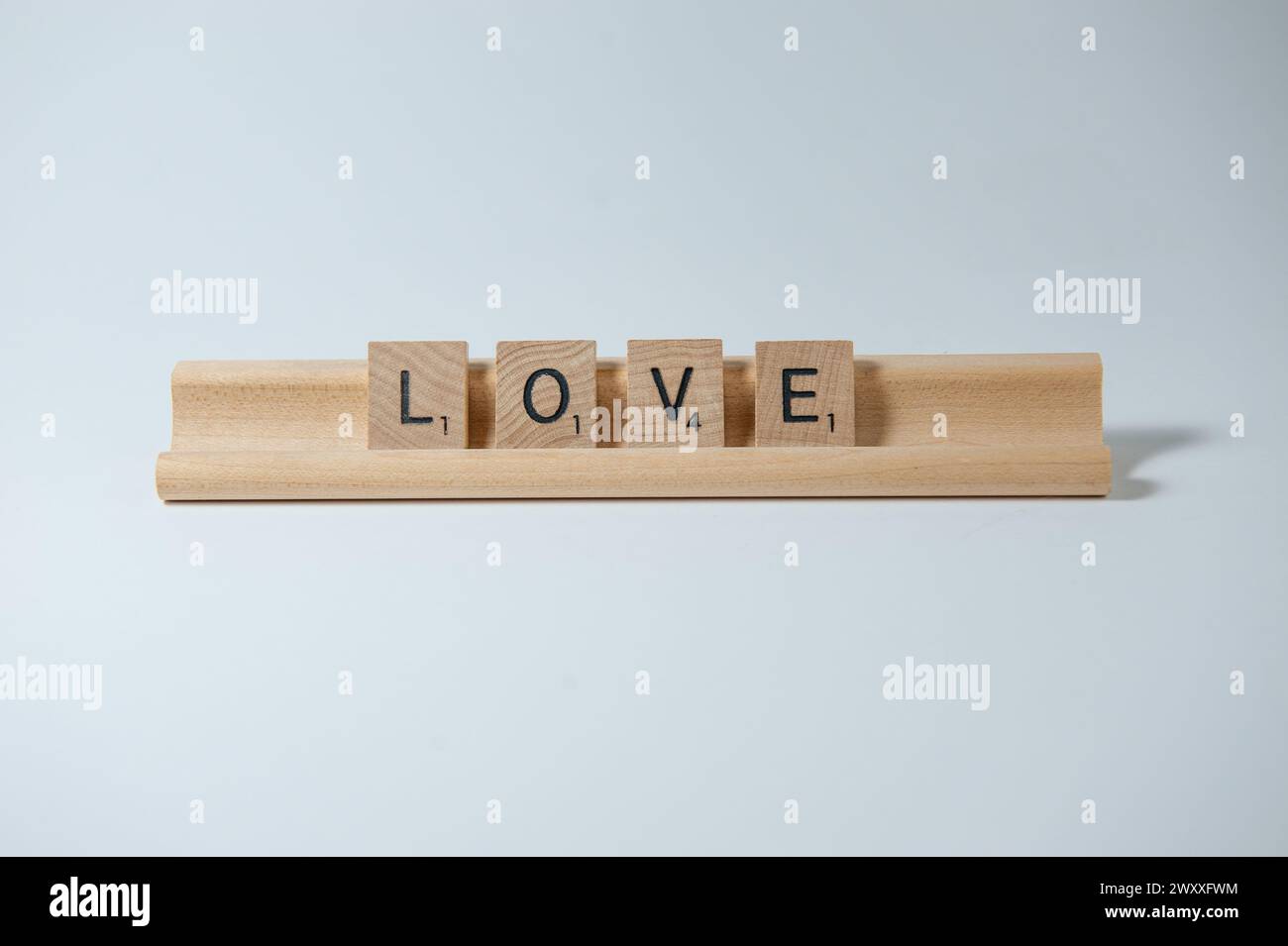 La parola "AMORE" in mattonelle di legno strapazzate su un vassoio di legno Foto Stock