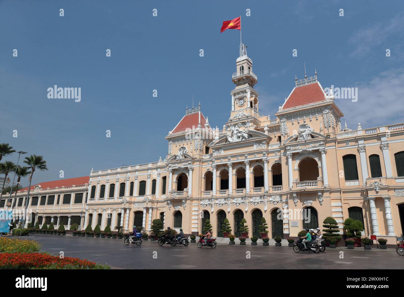 Vista esterna del Peoples Committee Building, sole e cielo blu, bandiera nazionale vietnamita, ho chi Minh City (Saigon), Vietnam Foto Stock