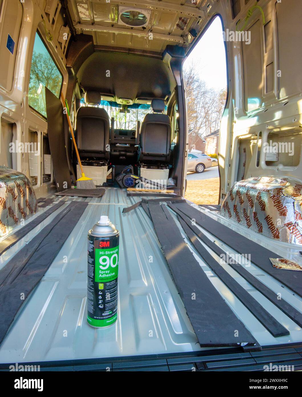 Materiale isolante in Thinsulate fissato al pavimento con adesivo spray nel furgone Mercedes Benz per il trasporto merci trasformato in un camper. Cary, Carolina del Nord. Foto Stock