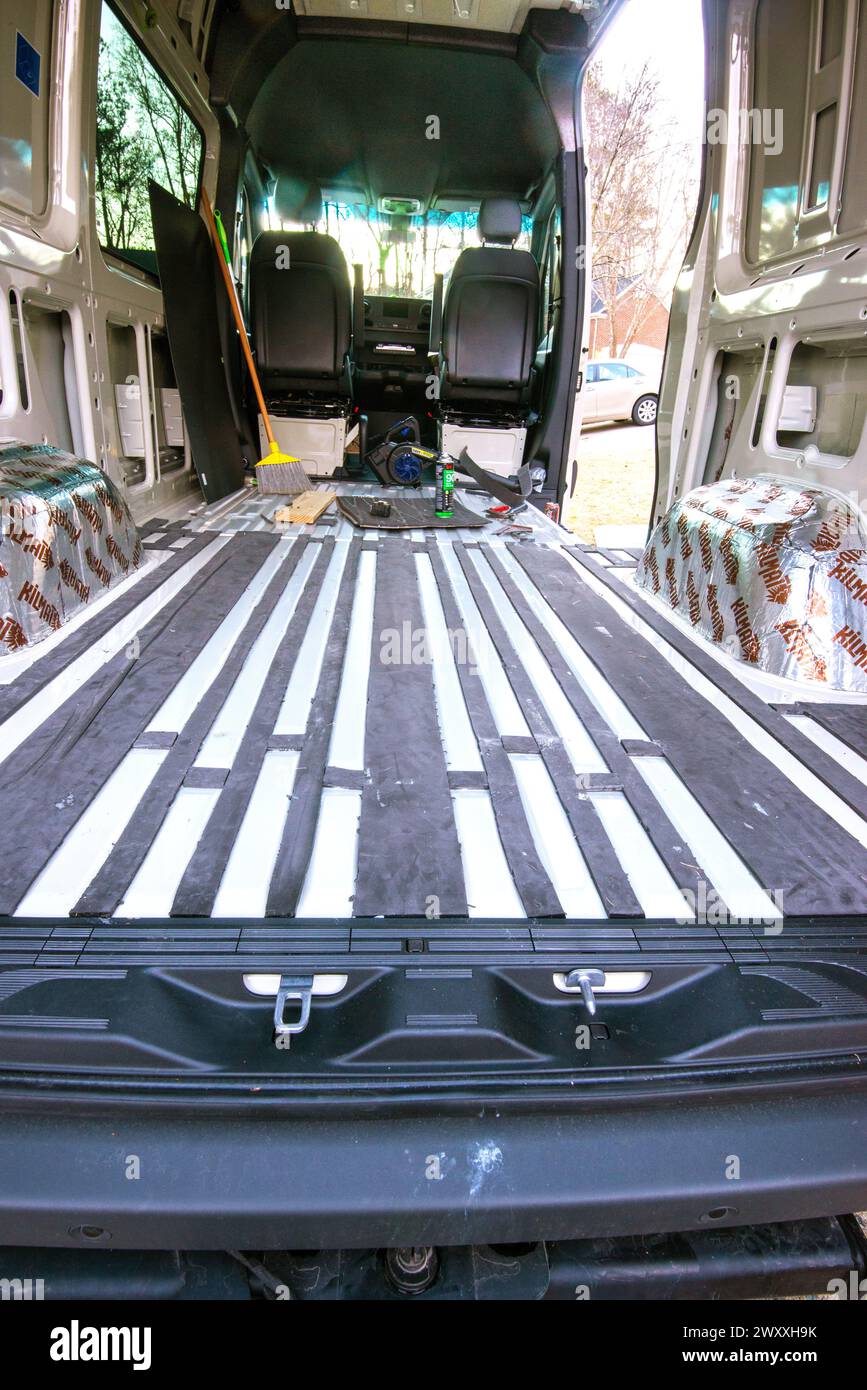 Materiale isolante in Thinsulate fissato al pavimento con adesivo spray nel furgone Mercedes Benz per il trasporto merci trasformato in un camper. Cary, Carolina del Nord. Foto Stock