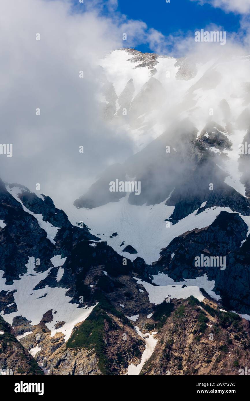 Nuvole e neve sull'imponente Monte Hotakadake nella catena montuosa Hida delle Alpi giapponesi settentrionali Foto Stock