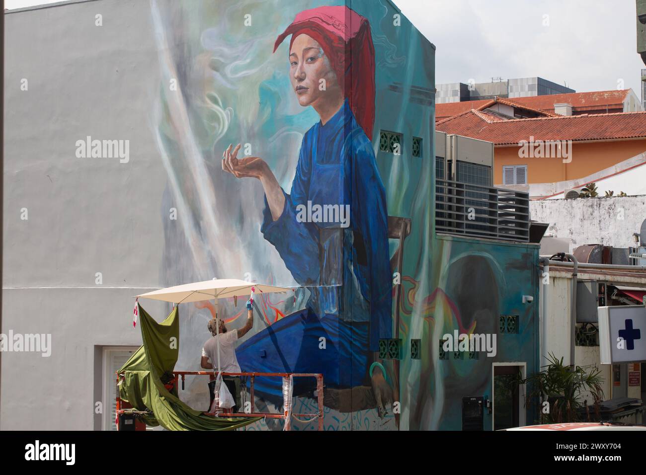 2 aprile 2024. Un pittore al sole caldo dipinge un muro di una donna Samsui a Chinatown. Singapore Foto Stock