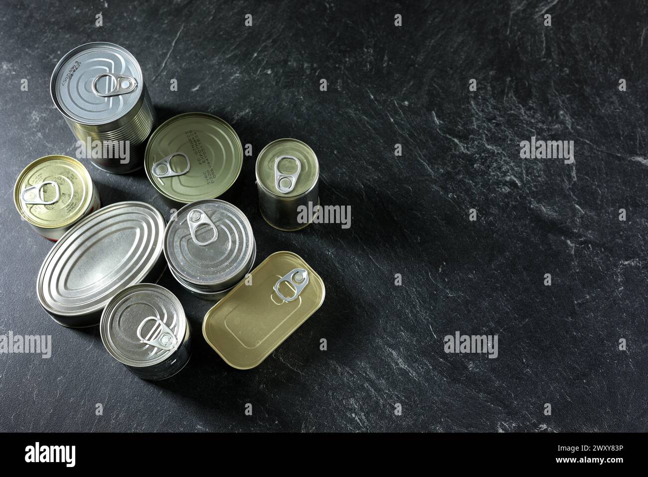 Vista superiore gruppo di alimenti inscatolati su tavolo in marmo nero, spazio copia per testo Foto Stock