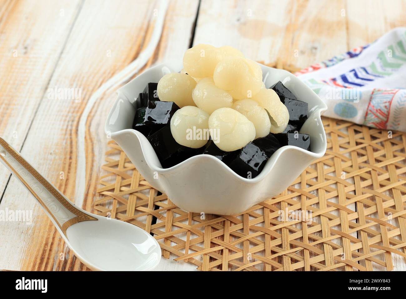 Gelatina di erba nera Mesona chinensis con condimento di frutta Longan. Gelatina nera vegetale con sciroppo di zucchero. Foto Stock