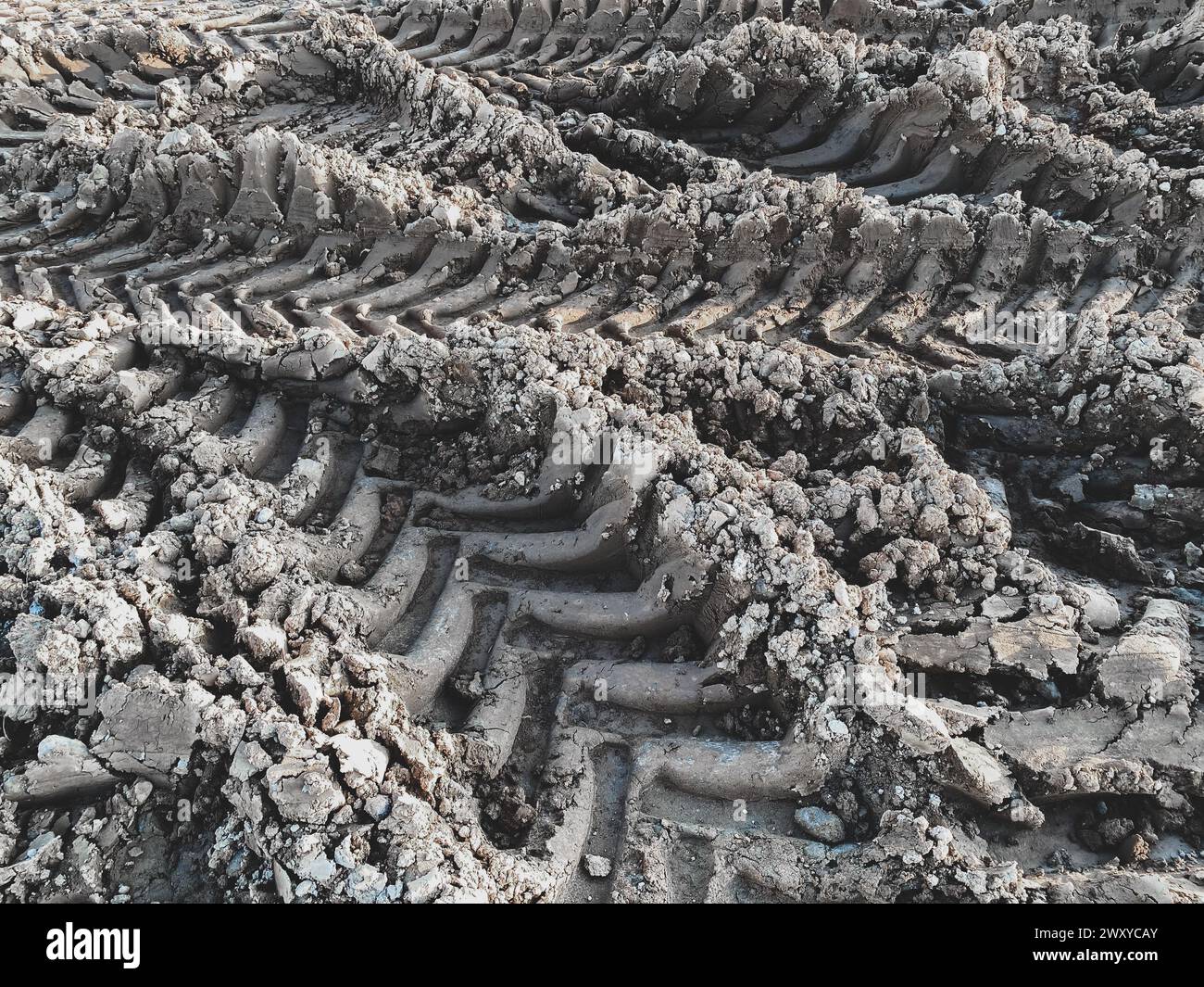 Segni degli pneumatici con battistrada profondo, messa a fuoco selettiva. Sfondo delle tracce di pneumatici nel fango. Concetto di cantiere Foto Stock