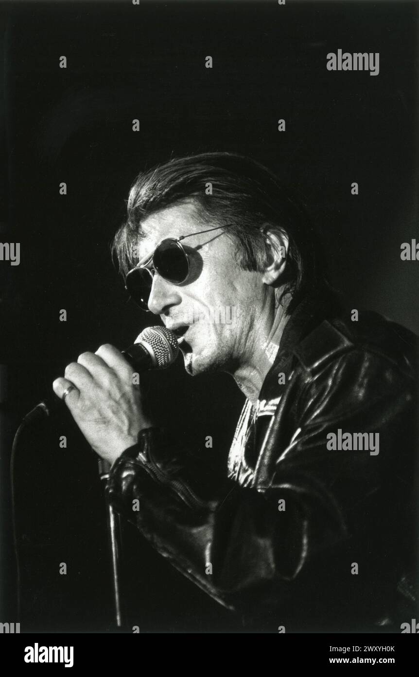 Reims (Francia nord-orientale), 1993: Jacques Dutronc in concerto, con occhiali da sole neri e una giacca di pelle, tenendo il microfono Foto Stock