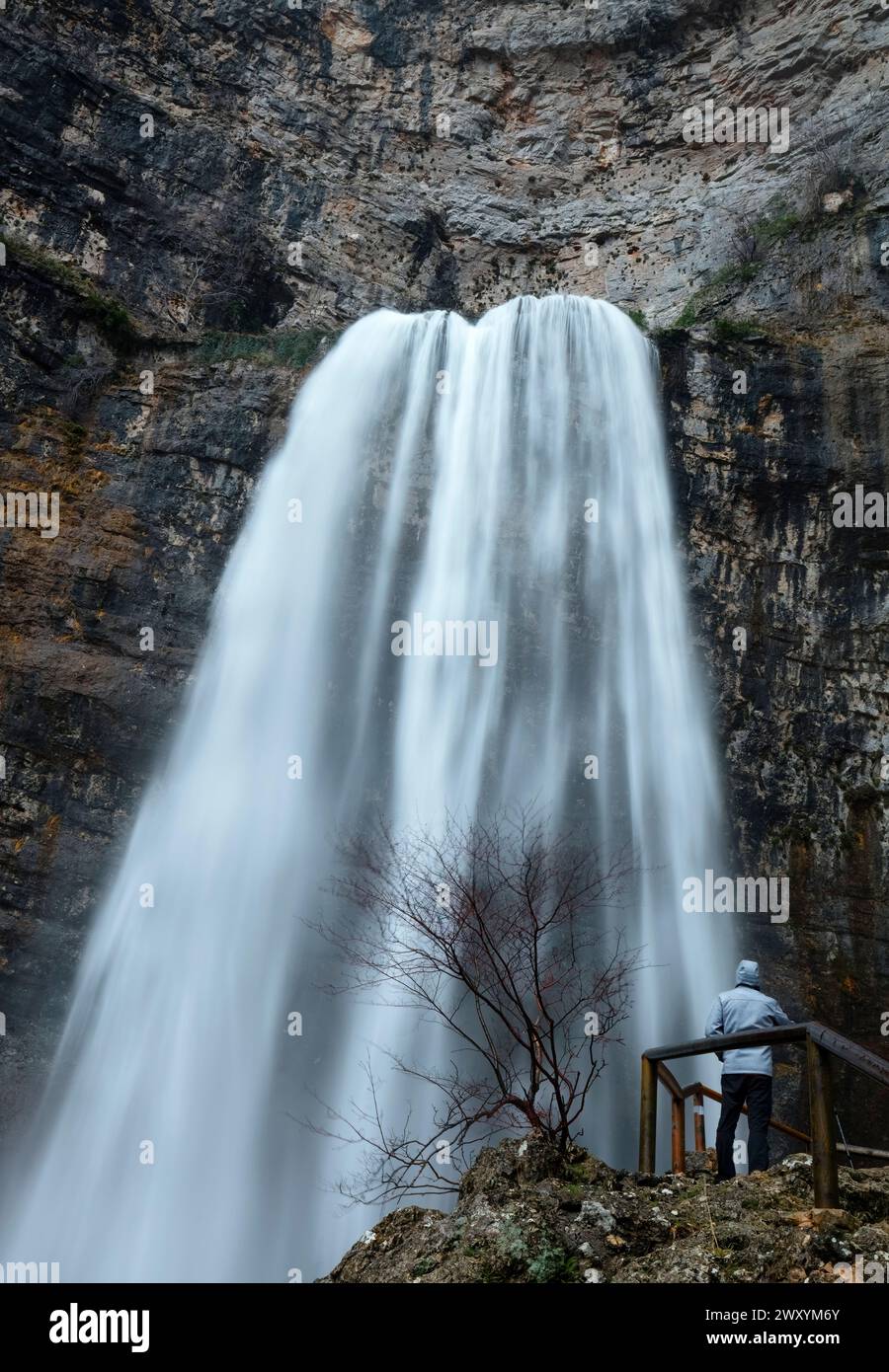 L'anonimo individuo si erge affascinato dal potente flusso della cascata del Rio Mundo, adagiato contro una scogliera aspra Foto Stock